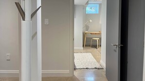 Un pasillo con un escritorio, una silla, un tapete blanco y una puerta que da a otra habitación.