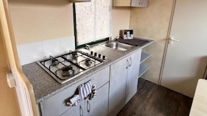 A compact kitchen with a gas stove, a sink, and cabinets. - Gargano Private Experience in the Heart of the Gargano - Nature & Sea (Villaggio Moresco Basso)