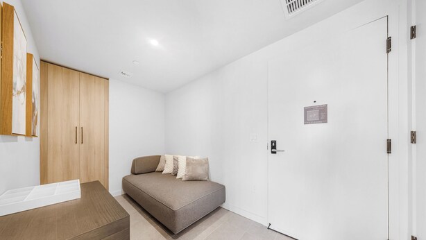 Ein modernes Zimmer mit einer Couch, einem Holzschrank und einer weißen Tür.