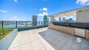 Eine Dachterrasse mit Blick auf die Stadt, ein Empfangsbereich und ein Schwimmbad.