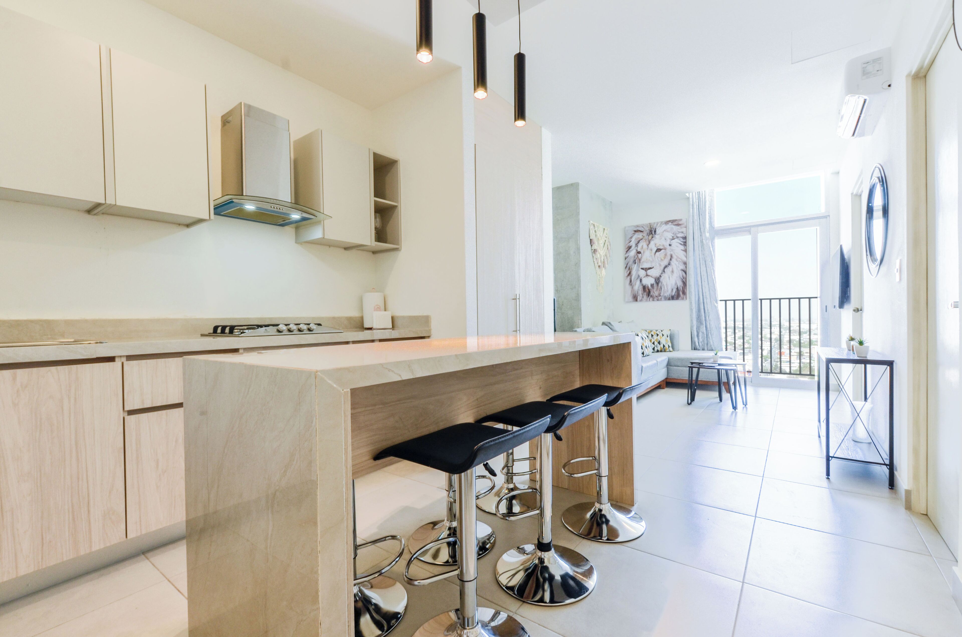 Uma cozinha moderna com ilha central, banquetas e iluminação pendente.