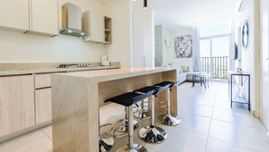 A modern kitchen with a central island, bar stools, and pendant lighting. - Arena Calzada (Monterrey)