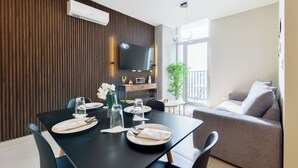 A dining area with a table set for two, a sofa, a TV, and a plant. - Arena Calzada (Monterrey)