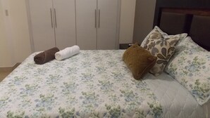 A bed with floral bedding, a brown pillow, and a white towel.