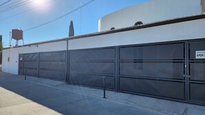 A building with large garage doors, a water tank on the roof, and a clear sky.
