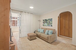 Ein Wohnzimmer mit einer Couch, einem Hocker und einem Bild an der Wand.