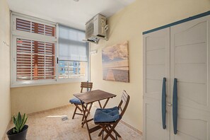 A small balcony with a table and chairs, a potted plant, and a view of buildings outside. - Vacation Apartment 'El Rincón De Ale' with Wi-Fi and Air Conditioning (Los Abrigos)