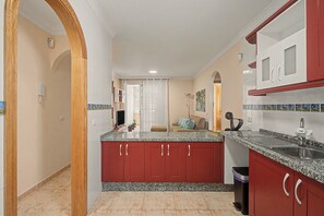 A kitchen with red cabinets, a granite countertop, and a stainless steel sink. - Vacation Apartment 'El Rincón De Ale' with Wi-Fi and Air Conditioning (Los Abrigos)