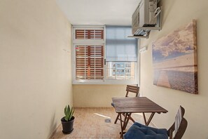 A small room with a window, a table, a chair, a potted plant, and a wall-mounted air conditioning unit. - Vacation Apartment 'El Rincón De Ale' with Wi-Fi and Air Conditioning (Los Abrigos)