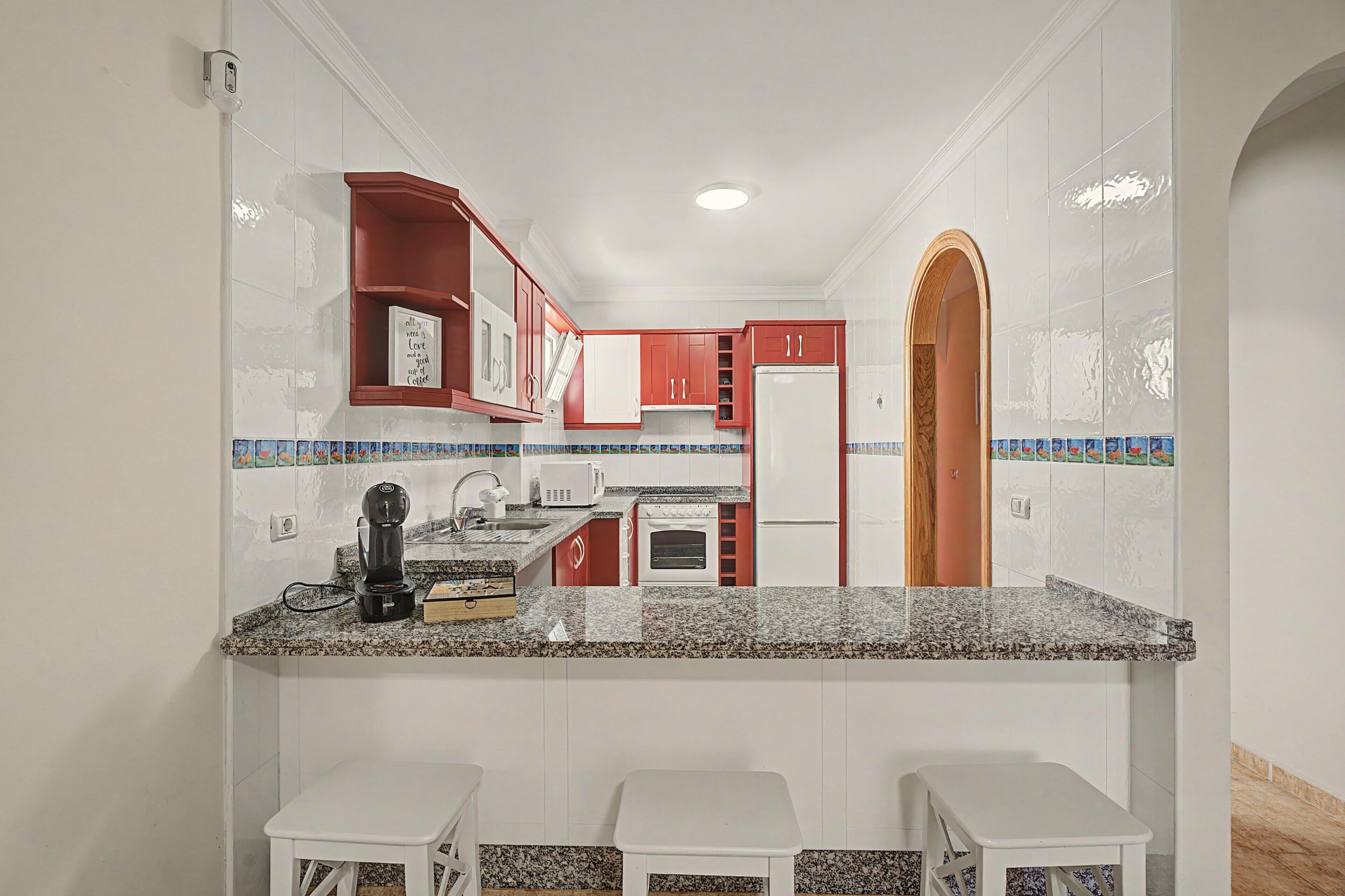 A compact kitchen with a granite countertop, white cabinetry, and a built-in oven.
