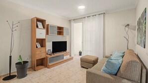 Ein modernes Wohnzimmer mit Flachbildfernseher, einer Holz-Unterhaltungsecke, einer Couch und einem Topf mit Pflanze.