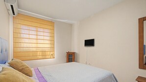 Ein Schlafzimmer mit einem Bett, einem Fenster, einem Fernseher und einem Holzschrank.