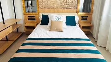 Une chambre d’hôtel avec un grand lit, une tête de lit en bois, deux tables de chevet, un miroir et un banc en bois.