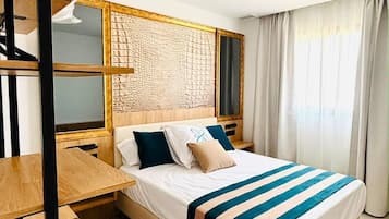 Une chambre d’hôtel moderne équipée d’un lit, d’un bureau en bois et d’une bibliothèque intégrée.
