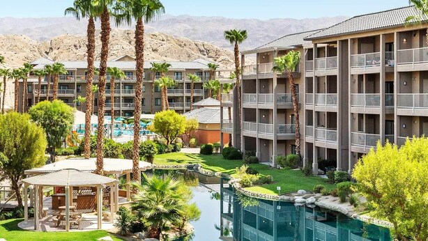 Et hotel med flere etager, swimmingpool og en have.