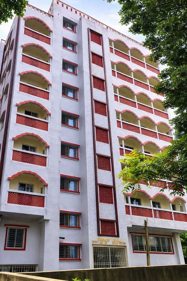 Un edificio de varios pisos con balcones, un cartel que indica 'Hotel' y una entrada con portón.