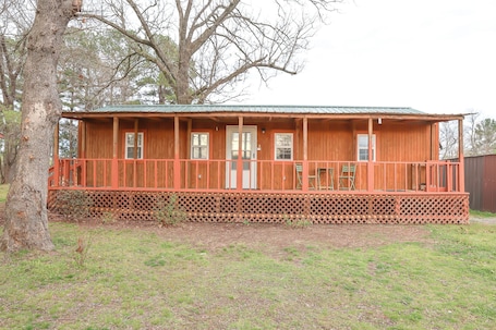 A wooden cabin with a porch, a door, and windows.