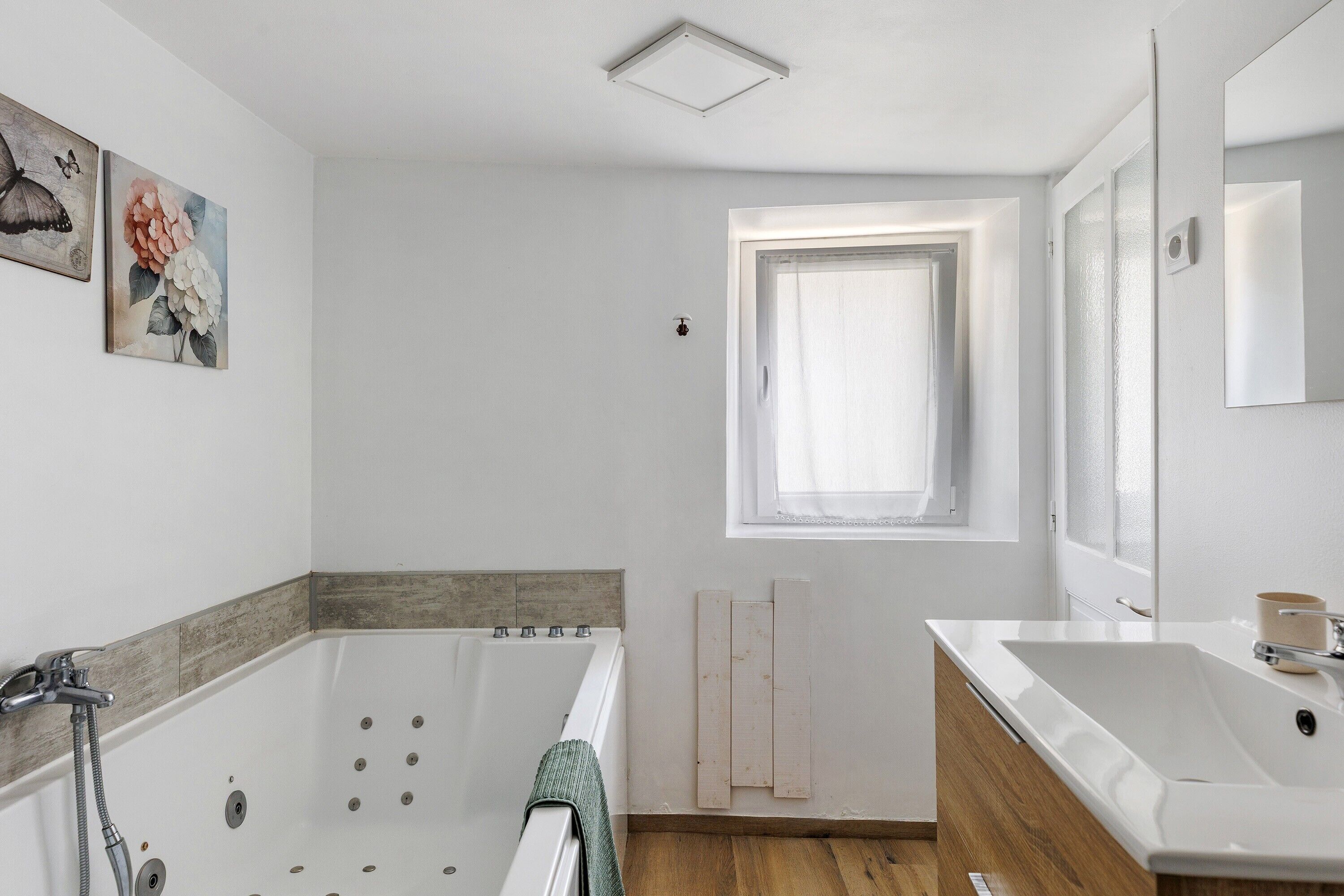 A modern bathroom with a bathtub, a sink, and a window.