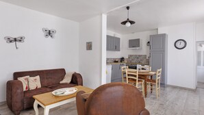 Una sala de estar con un sofá marrón, una mesa de centro de madera y un comedor con una mesa y sillas de madera.