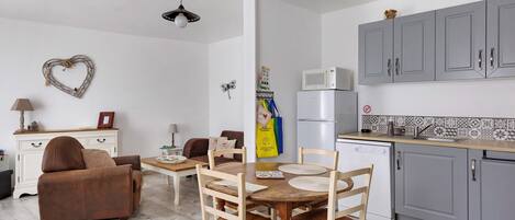 A compact living space with a dining area, kitchenette, and a heart-shaped decoration on the wall.