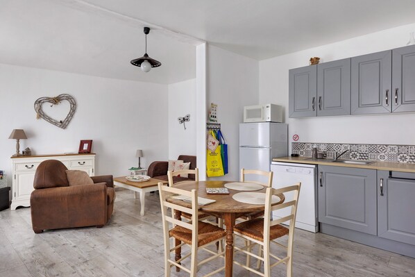 A compact living space with a dining area, kitchenette, and a heart-shaped decoration on the wall.