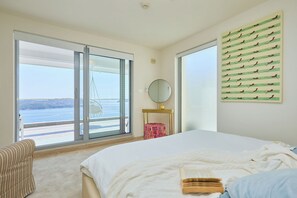 A bedroom with a large bed, a view of the sea through a sliding door, a round mirror, and a wall art piece. - Hedera Estate, Villa Hedera XXIV (Zaton Mali)