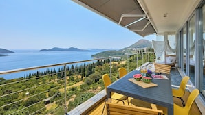 Un balcone con tavolo, sedie e vista sul mare e sulle montagne.