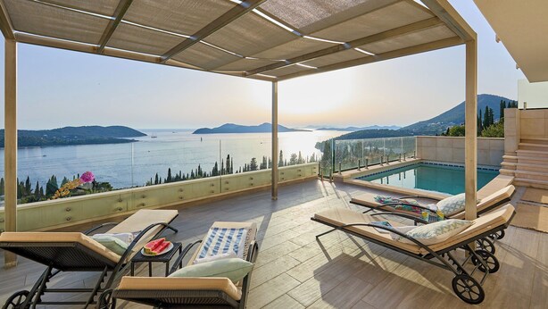 Un'area esterna coperta con poltrona relax e piscina.