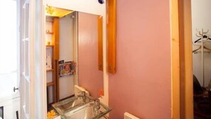 A bathroom with a glass sink, wooden beams, and a pink wall. - Bien situe (Paris)