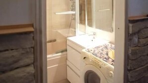 A compact bathroom with a washing machine, a glass shower enclosure, and a mirror above the sink. - Bien situe (Paris)