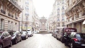 A cobblestone street lined with parked cars and historic buildings. - Bien situe (Paris)