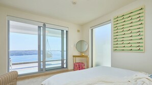 A bedroom with a large bed, a view of the sea through a sliding door, a round mirror, and a wall art piece. - Hedera Estate, Villa Hedera XXII (Zaton Mali)