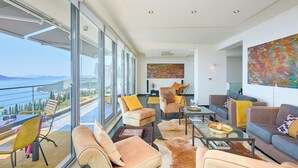 A spacious living area with a large window overlooking a scenic view, furnished with sofas and chairs, and a coffee table. - Hedera Estate, Villa Hedera XXII (Zaton Mali)