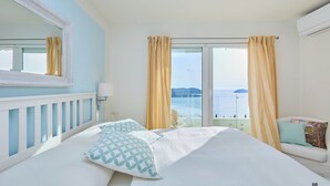 Een hotelkamer met een bed, een slaapbank, een groot raam met gordijnen, een spiegel en een airconditioning.