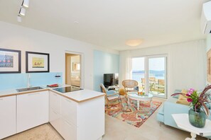 A modern kitchen with white cabinets, a sink, and a dining area with a table and chairs. There is a large window with a view of the sea. - Hedera Estate, Villa Hedera XXI (Zaton Mali)