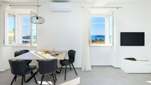 Una habitación moderna con una mesa de comedor, sillas, televisor y ventanas amplias con vistas.