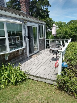 Une maison avec une terrasse en bois, une table de patio et une boîte aux lettres blanche.