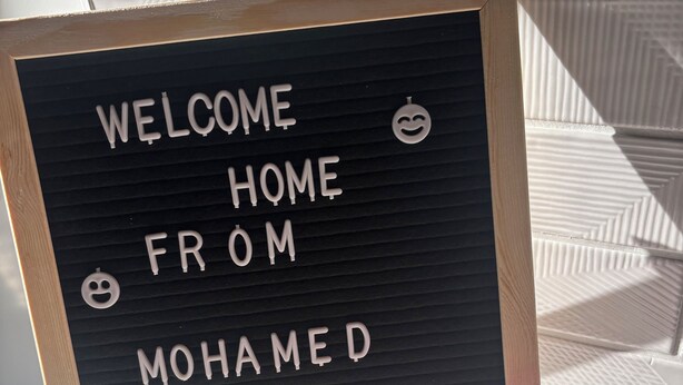 Ein Willkommensschild mit dem Schriftzug 'WELCOME HOME FROM MOHAMED' und zwei Smileys.