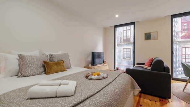 Ein modernes Hotelzimmer mit einem großen Bett, einem Fernseher, einem Essbereich und Blick auf die Stadt.