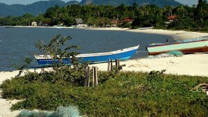 A beach with boats, a sandy shore, and a mountain in the background. - Villa Di Mare II-Piscina e churrasqueira (São Francisco do Sul)