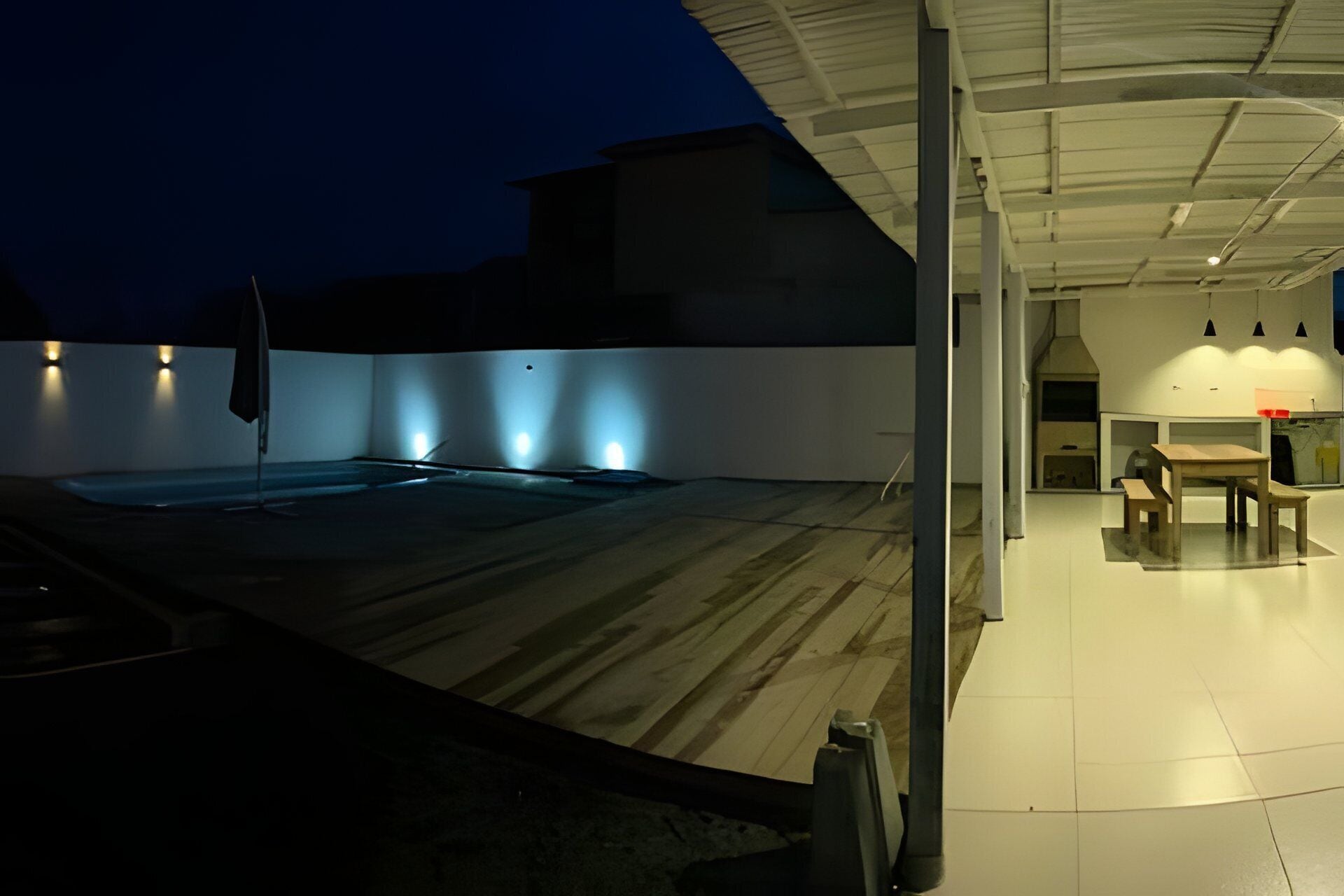 Una terraza en la azotea con piscina, zona de comedor y espacio de estar cubierto.