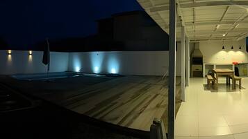 Una terraza en la azotea con piscina, zona de comedor y espacio de estar cubierto.