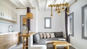 Ett modernt kök med träskåp, en matplats med en bänk, en grå hörnsoffa och en hängande lampa.