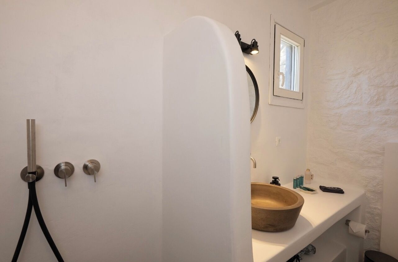 Une salle de bain avec une baignoire blanche, un lavabo en bois et une petite fenêtre.