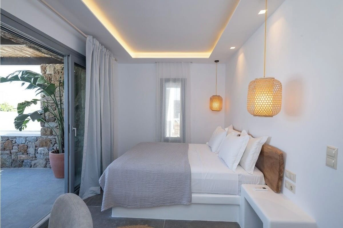 A modern bedroom with a bed, bedside table, and a large window.