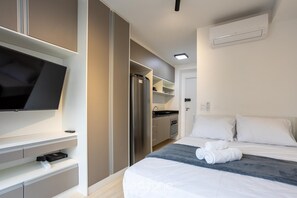 A hotel room with a bed, a flat-screen TV, a mini kitchen, and a walk-in closet. - Studios in Build. w/ Pool in Bela Vista SP - Sncs (São Paulo)