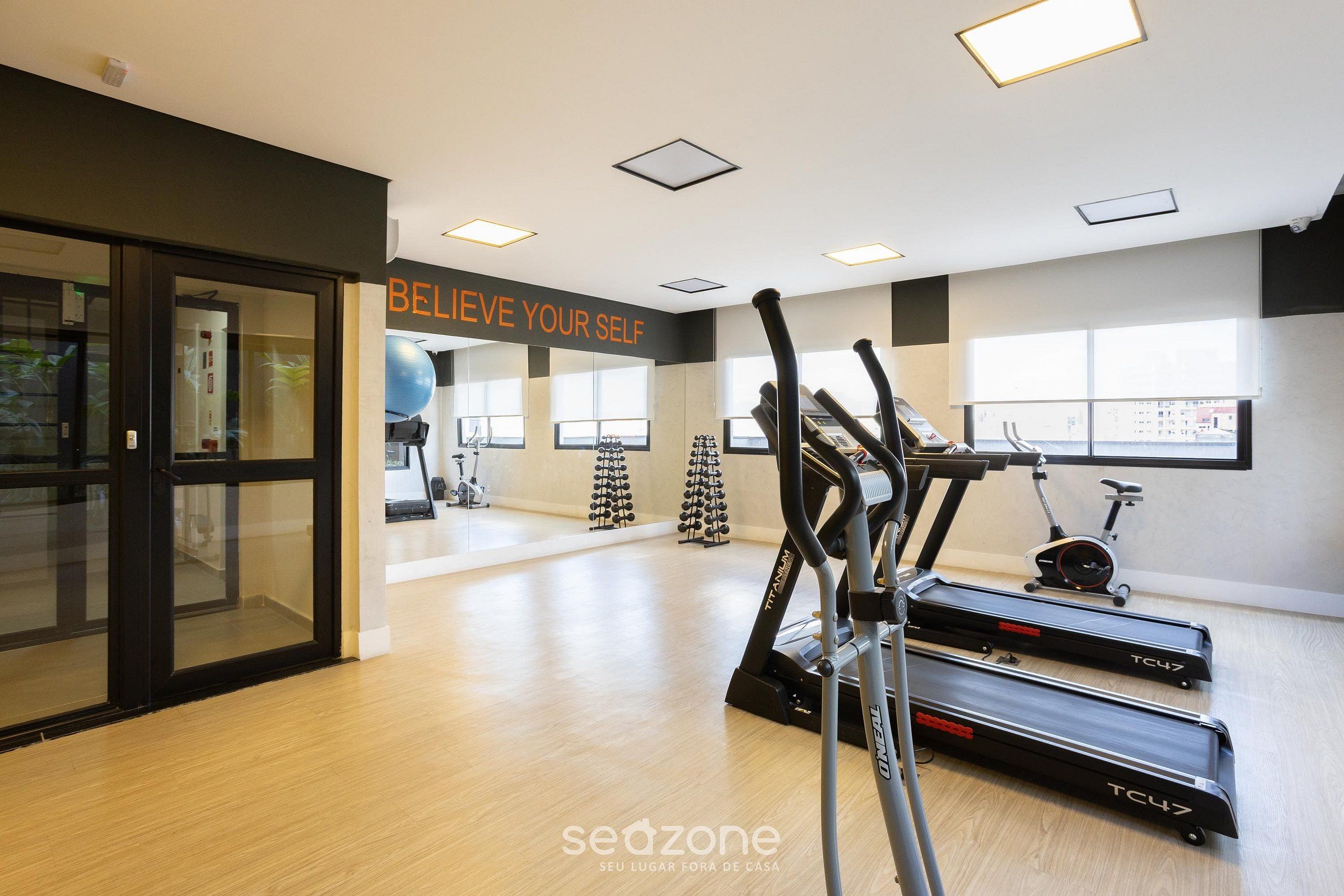 A gym with treadmills, exercise bikes, and a motivational wall.