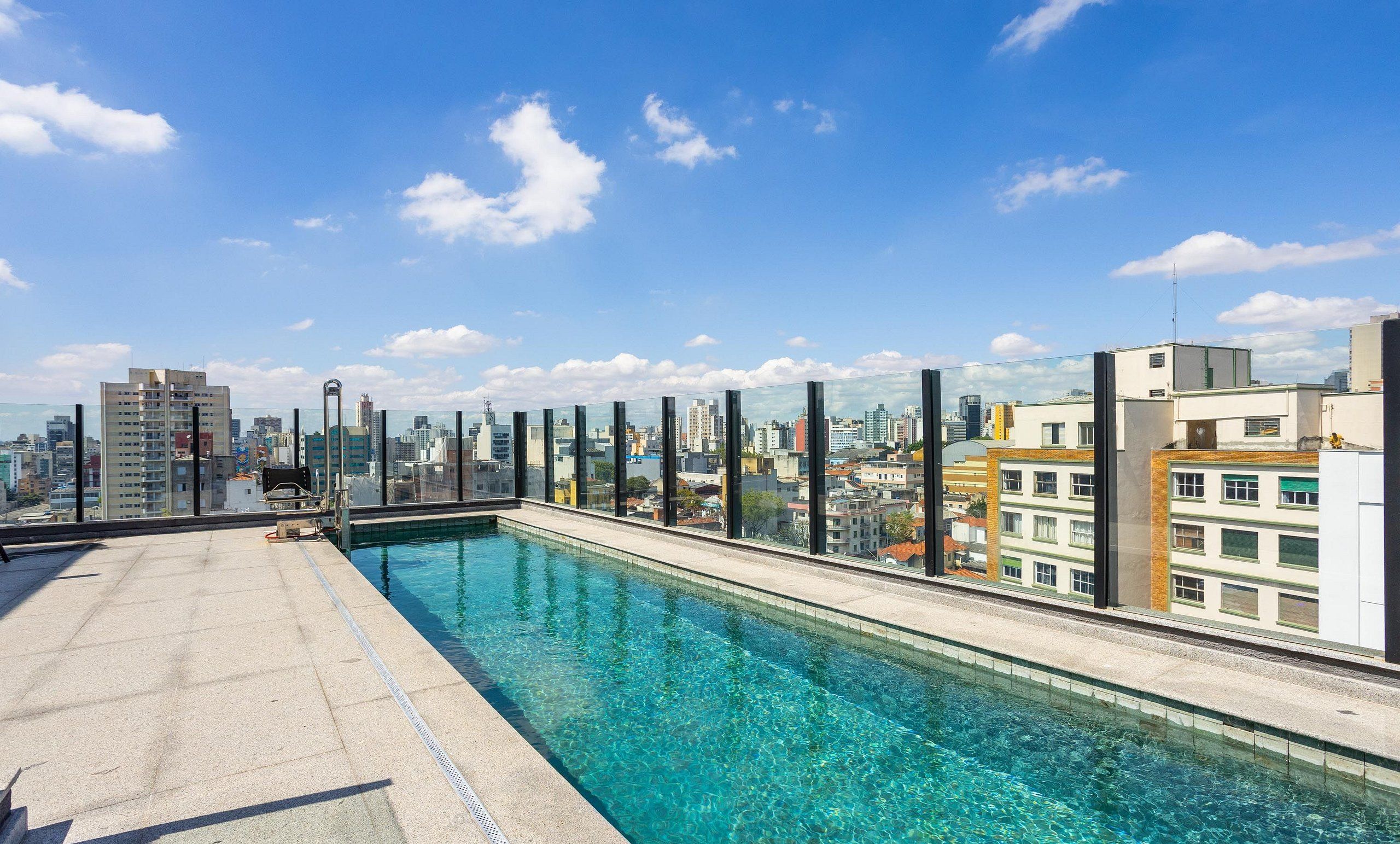 A rooftop pool with a cityscape view, surrounded by glass railings.