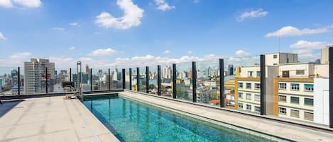 A rooftop pool with a cityscape view, surrounded by glass railings.
