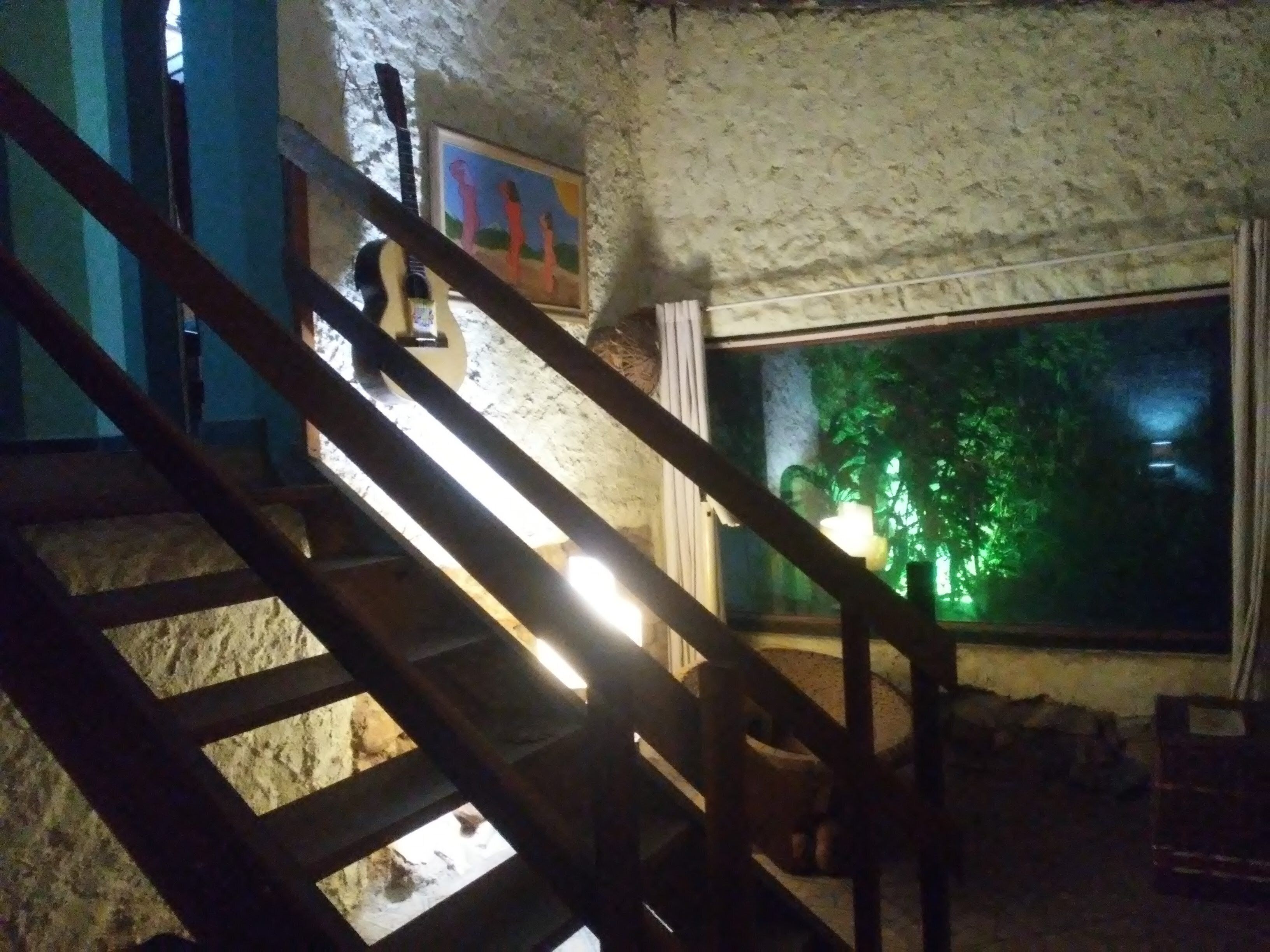 A staircase with a wooden handrail and a window with a view of a tree.
